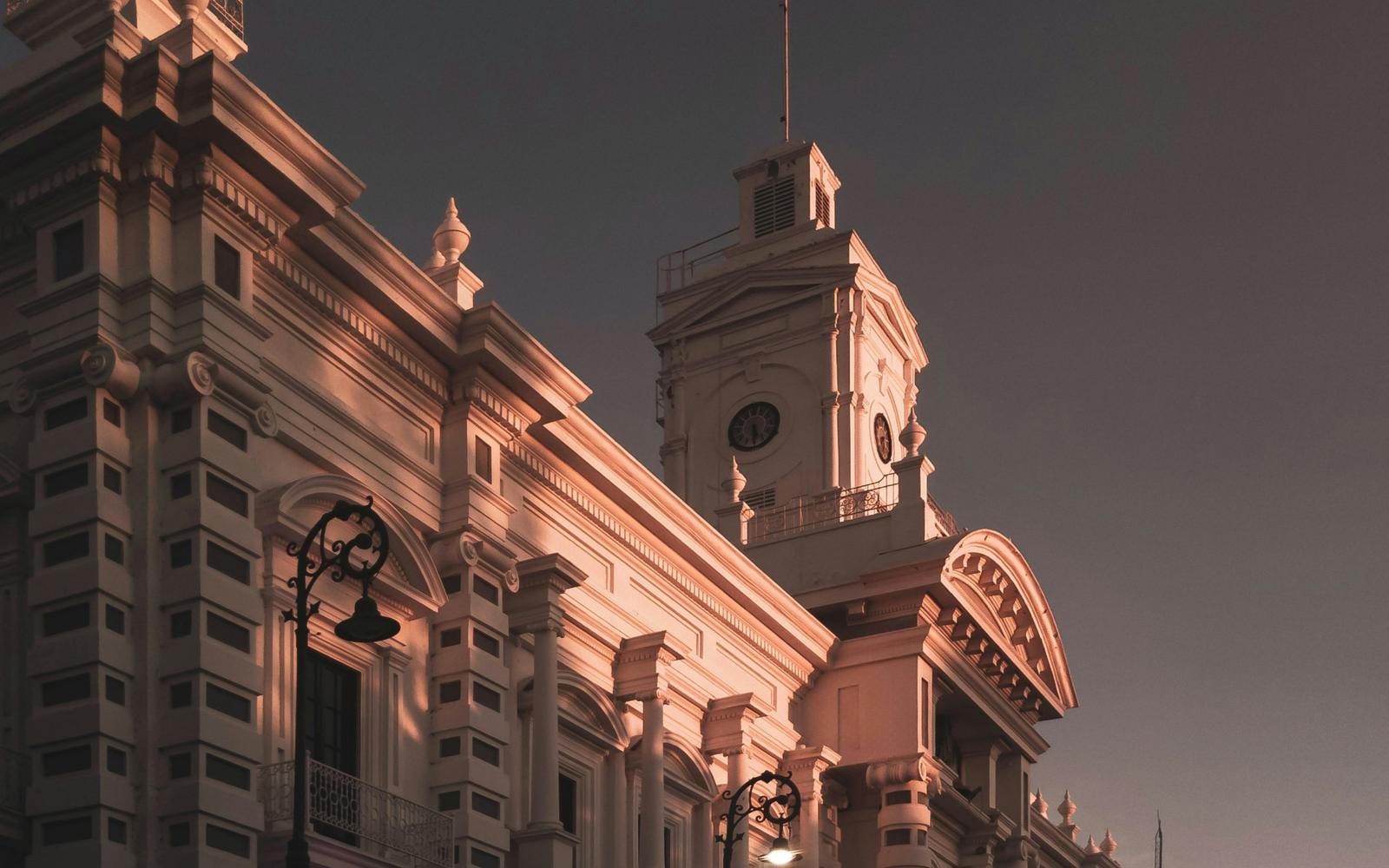 Fachada de un palacio de gobierno con torre de reloj al atardecer